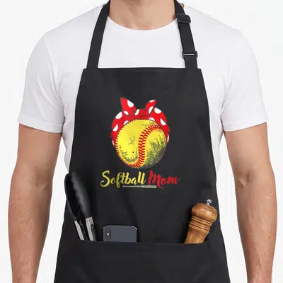 Player mother's day aprons - Yellow softball with red polka dot bow and Softball Mom text with small bat — shown on a black cotton canvas apron against a white background