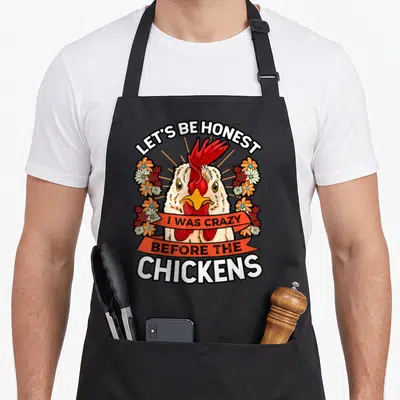 Before chicken apron - Cartoon chicken head with red comb and flowers surrounding text LET'S BE HONEST, I WAS CRAZY — shown on a black cotton canvas apron against a white background