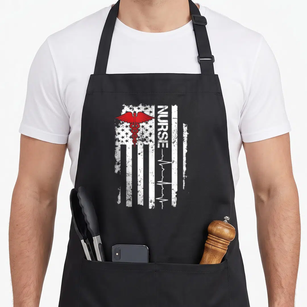 Pulse nurse apron - Distressed white flag with red caduceus and vertical NURSE text ending in heartbeat line — shown on a black cotton canvas apron against a white background