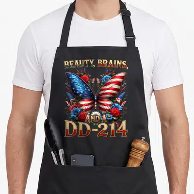 Veteran floral apron - Butterfly with flag wings surrounded by flowers and dd-214 text in red white blue gold — shown on a black cotton canvas apron against a white background