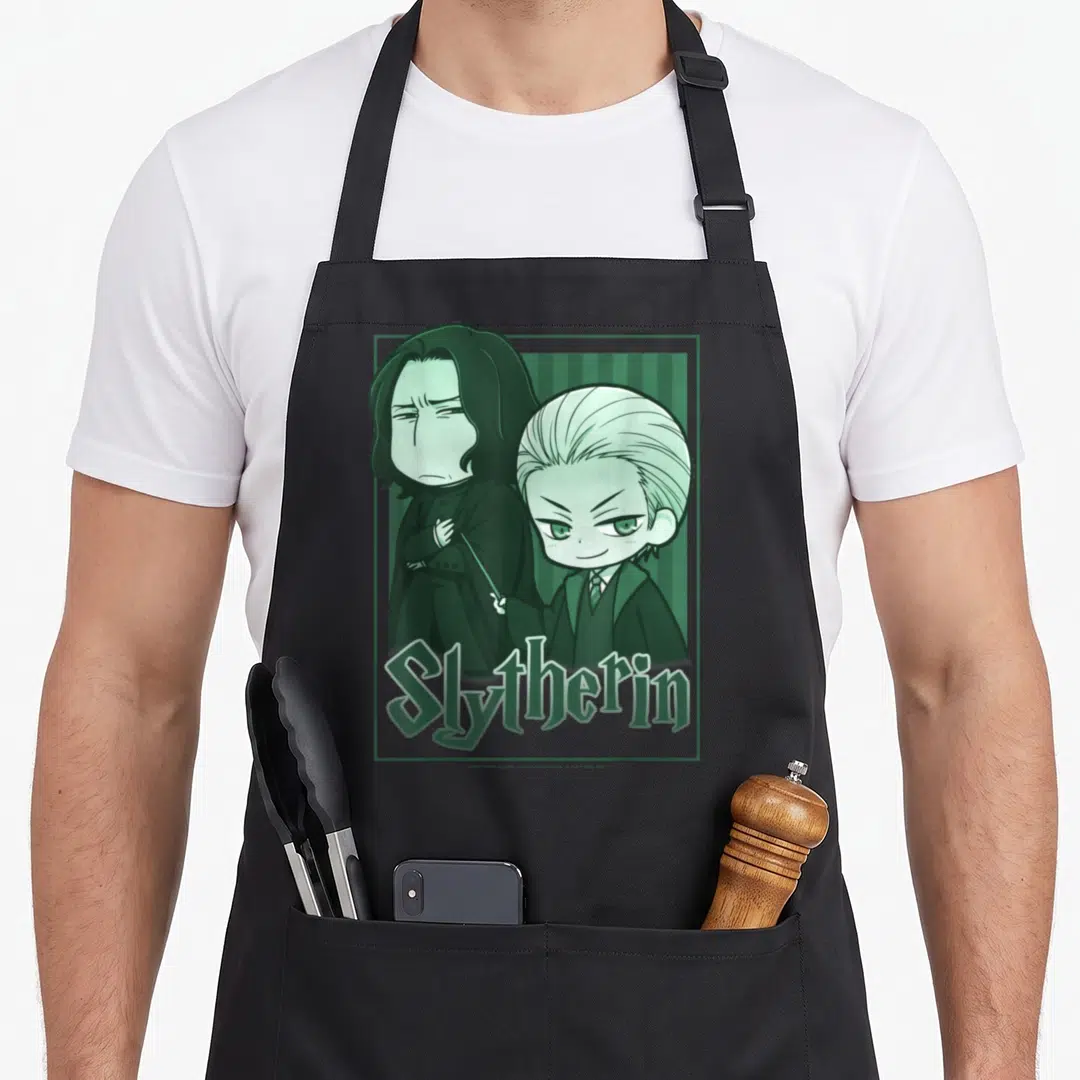 Chibi potter apron - Two men in green monochrome standing before vertical stripes with Slytherin text below — shown on a black cotton canvas apron against a white background