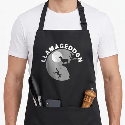 Llamageddon llama dad apron - LLAMAGEDDON text over moon, two llamas on cliff, falling person silhouette — shown on a black cotton canvas apron against a white background