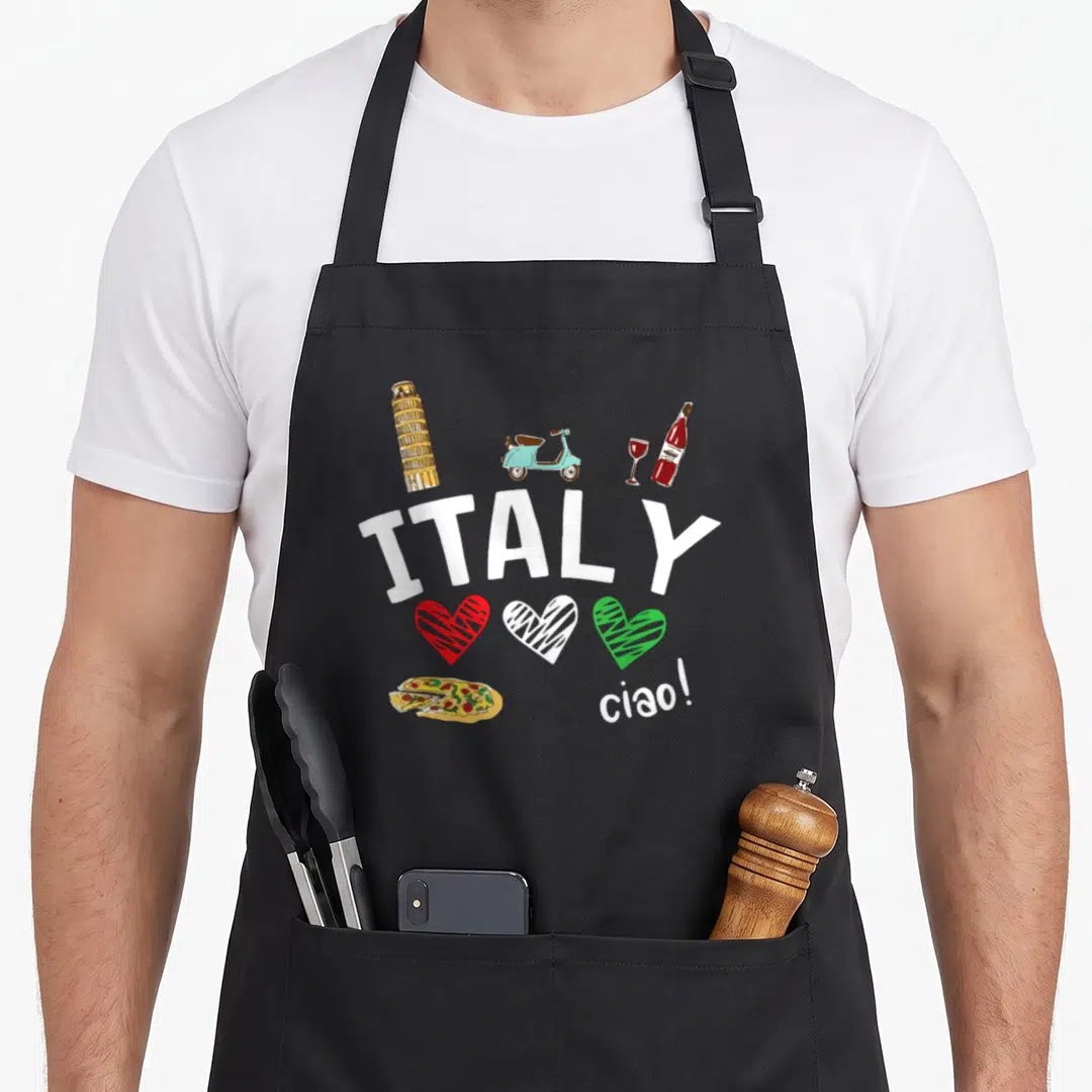 Culture italy apron - Cartoon Italy design with tower, scooter, wine, three hearts, pizza, and ciao text — shown on a black cotton canvas apron against a white background
