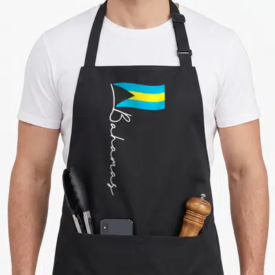 Bahamas pride apron - Bahamas flag with vertical white script below in blue, yellow, black, and white — shown on a black cotton canvas apron against a white background