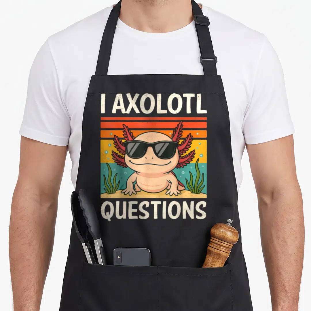 Youth axolotl question apron - Cartoon axolotl in sunglasses with I AXOLOTL QUESTIONS text on retro striped background — shown on a black cotton canvas apron against a white background