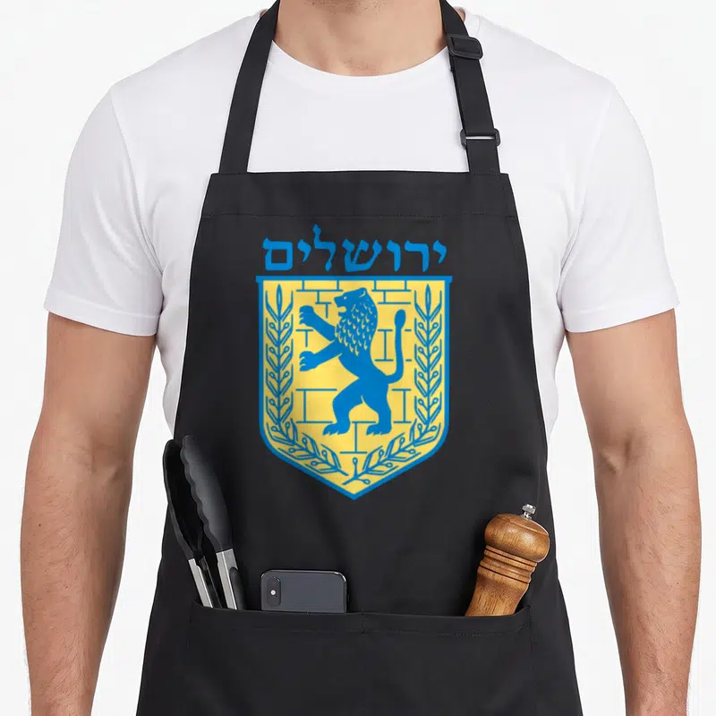 Jerusalem jewish aprons - Blue Hebrew text over yellow shield with blue lion and two olive branches — shown on a black cotton canvas apron against a white background