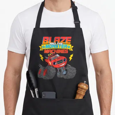 Blaze monster machine apron - Red cartoon monster truck with BLAZE AND THE MONSTER MACHINES text and yellow lightning — shown on a black cotton canvas apron against a white background