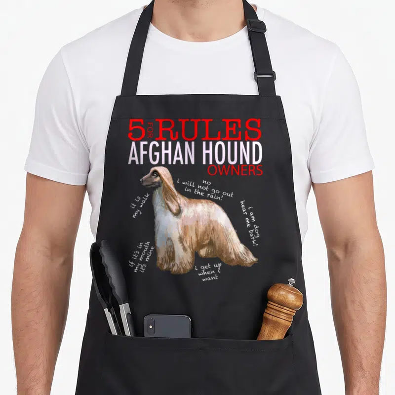 Rule afghan apron - Cartoon Afghan hound surrounded by humorous rule text in red and white — shown on a black cotton canvas apron against a white background