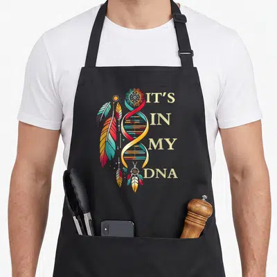 Funny dna pride apron - Colorful DNA helix with feathers, dreamcatcher, and It's In My DNA text — shown on a black cotton canvas apron against a white background