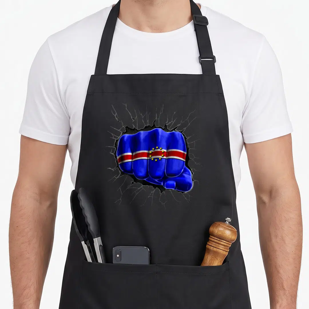 Fist cape verde apron - Realistic fist painted with Cape Verde flag colors punching through a cracked grey wall — shown on a black cotton canvas apron against a white background