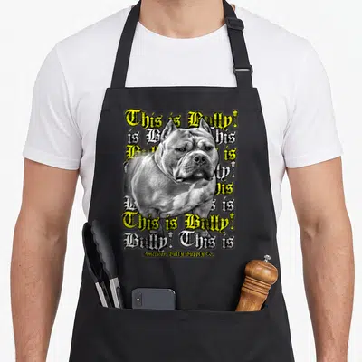Bully top dog aprons - Realistic grey dog overlapping repeated This is Bully! text in yellow and white Gothic font — shown on a black cotton canvas apron against a white background
