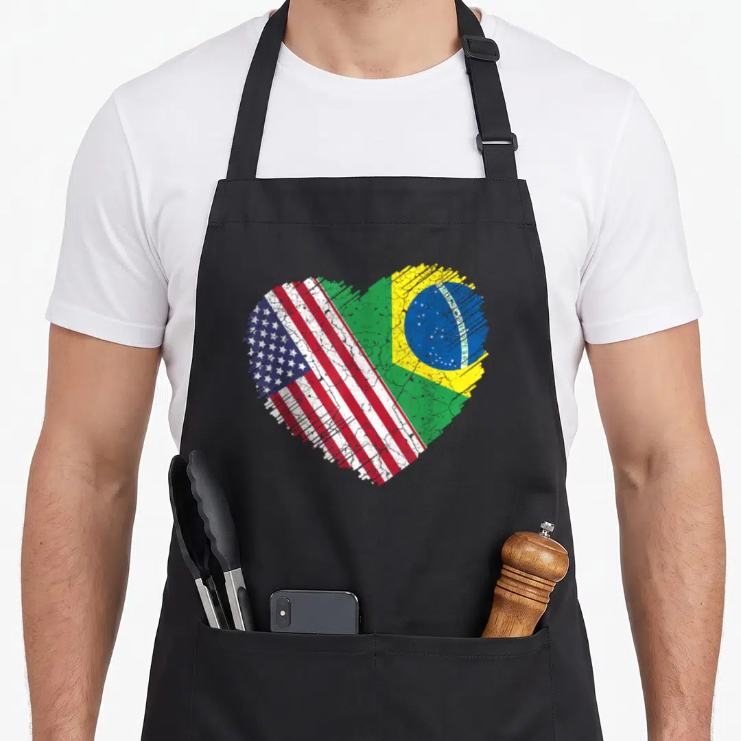 Brazil pride american flag apron - Distressed heart split diagonally showing USA and Brazil flags with Ordem e — shown on a black cotton canvas apron against a white background