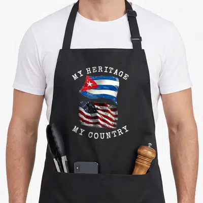Heritage country apron - Cuban and USA flags with MY HERITAGE MY COUNTRY text in distressed red white blue — shown on a black cotton canvas apron against a white background