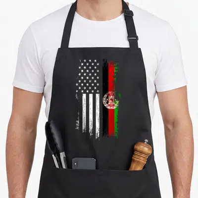 Afghanistan american flag apron - Two distressed flags side-by-side in white, black, red, and green paint strokes — shown on a black cotton canvas apron against a white background