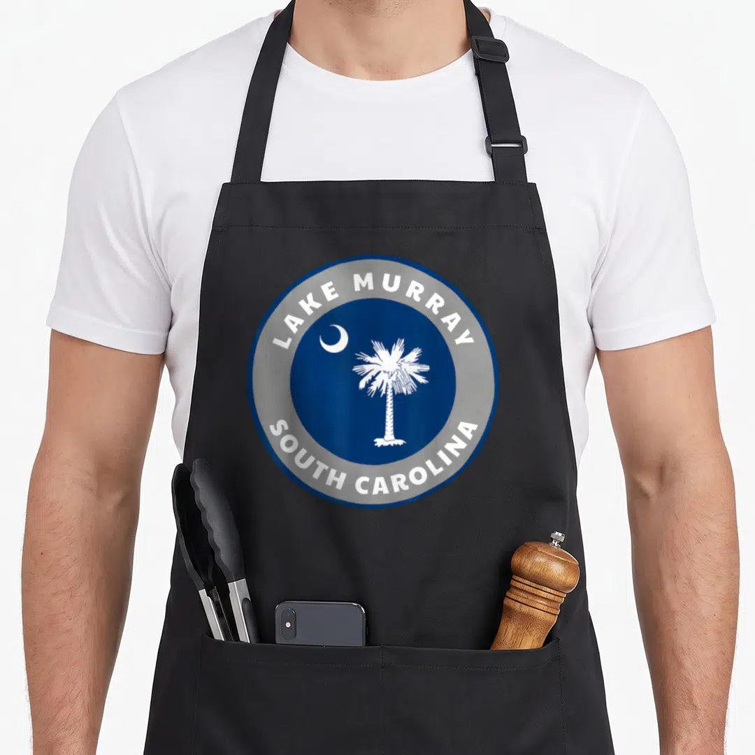 Murray pride apron - Blue circle with white palm tree and moon surrounded by text ring — shown on a black cotton canvas apron against a white background