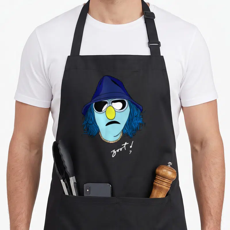 Zoot face apron - Blue cartoon character head with hat, sunglasses, yellow nose, and zoot! text — shown on a black cotton canvas apron against a white background