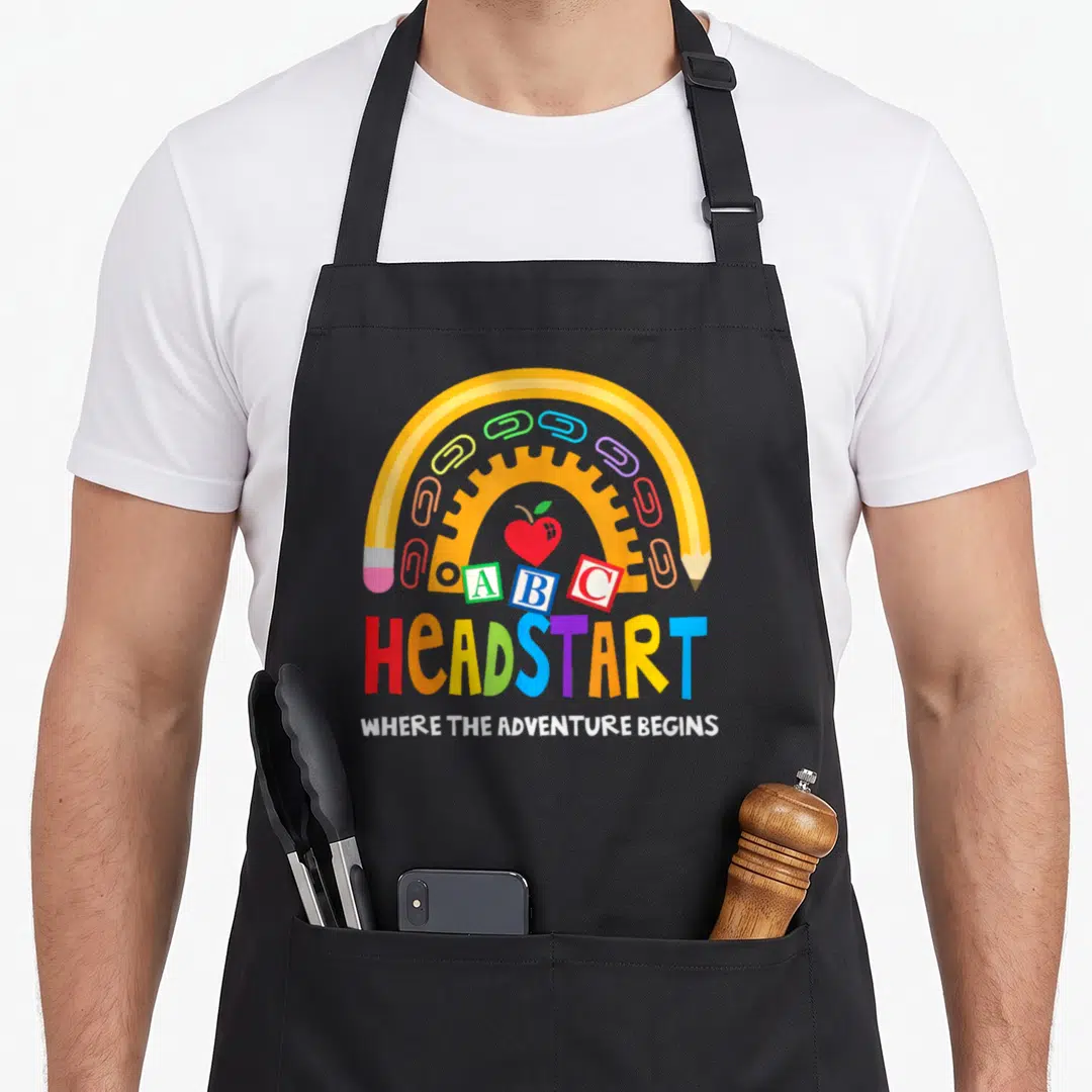 Early preschool teacher apron - Yellow pencil arch with paperclips, apple, ABC blocks, and multi-colored Headstart text — shown on a black cotton canvas apron against a white background