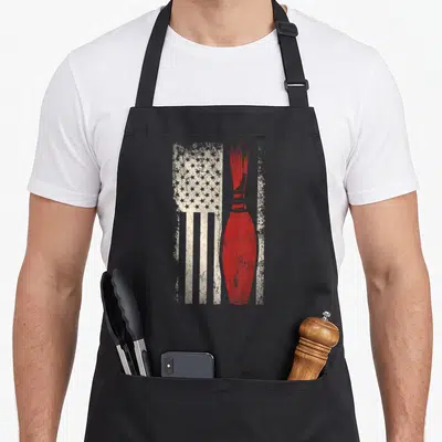 Bowler american flag apron - Red bowling pin superimposed over distressed white stars and stripes — shown on a black cotton canvas apron against a white background
