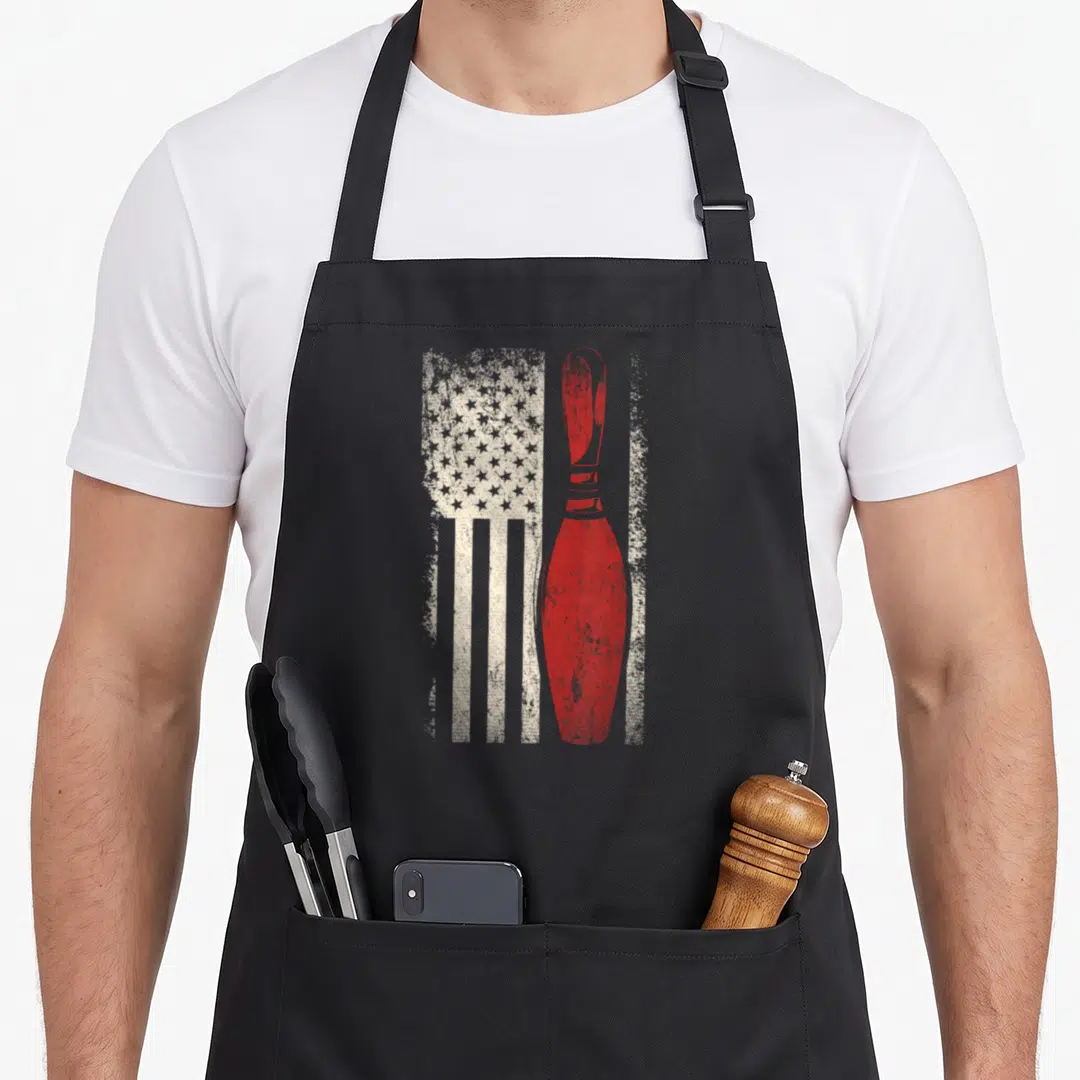 Bowler american flag apron - Red bowling pin superimposed over distressed white stars and stripes — shown on a black cotton canvas apron against a white background