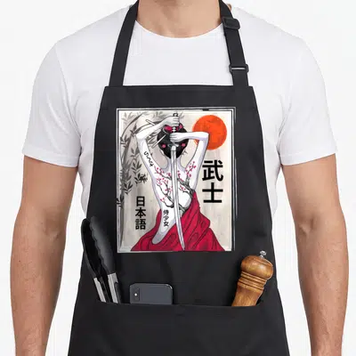 Culture cherry apron - Woman holding katana vertically with kanji, red sun, bamboo, and back tattoos in line art — shown on a black cotton canvas apron against a white background