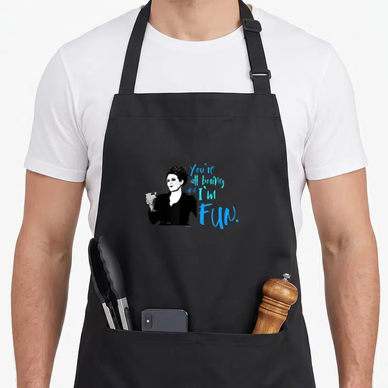 Boring grace apron - Black and white woman holding a glass beside blue stacked text You're all boring and I'm Fun — shown on a black cotton canvas apron against a white background