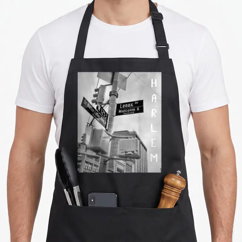 Harlem new york apron - Black and white street sign photo with vertical HARLEM text and Lenox Av signage — shown on a black cotton canvas apron against a white background