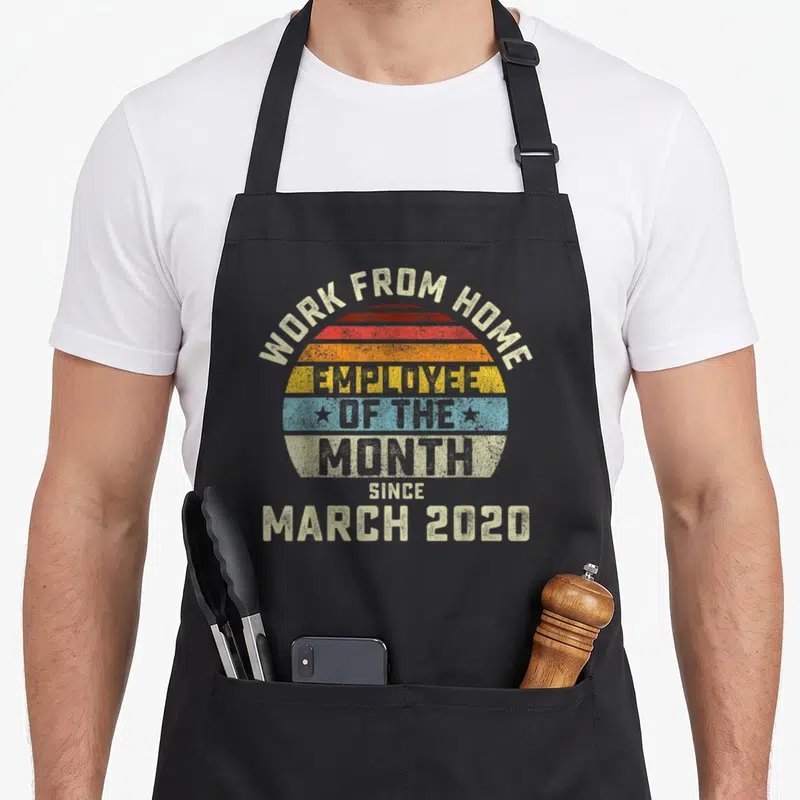 Funny month employee aprons - Retro striped sun with Work From Home Employee of the Month Since March 2020 text — shown on a black cotton canvas apron against a white background