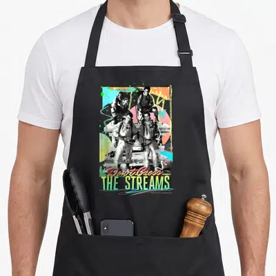 Stream cross apron - Retro poster with four people, colorful geometric shapes, and text Don't Cross THE STREAMS — shown on a black cotton canvas apron against a white background