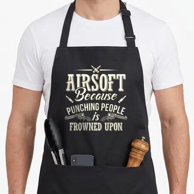 Funny airsoft gun apron - Beige stacked text reading AIRSOFT Because PUNCHING PEOPLE is FROWNED UPON with crossed — shown on a black cotton canvas apron against a white background