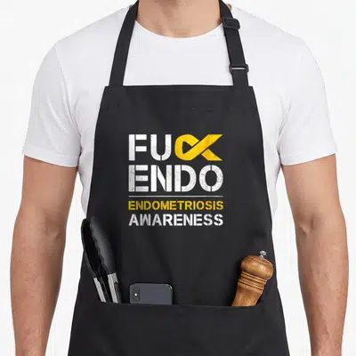 Endometriosis awareness ribbon apron - FUCK ENDO text with yellow ribbon replacing K and Endometriosis Awareness below — shown on a black cotton canvas apron against a white background