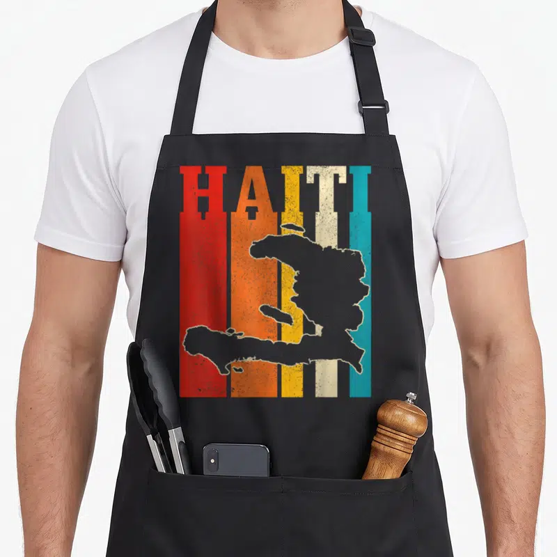 Island pride apron - HAITI text over five colored stripes with grey map silhouette overlay — shown on a black cotton canvas apron against a white background
