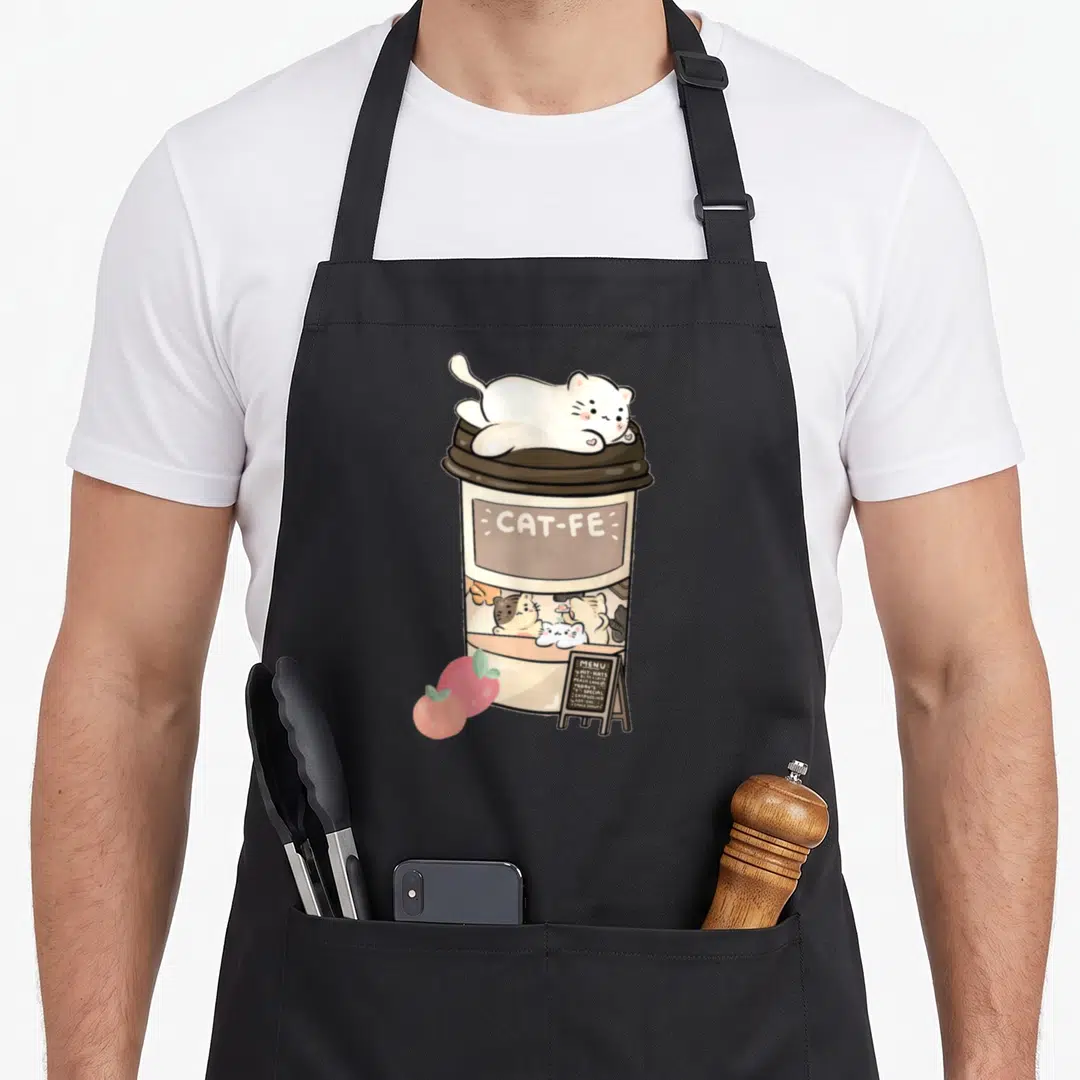 Cafe kitty cat apron - Cartoon coffee cup with cats, CAT-FE text, peaches, and menu board in beige brown white pink — shown on a black cotton canvas apron against a white background