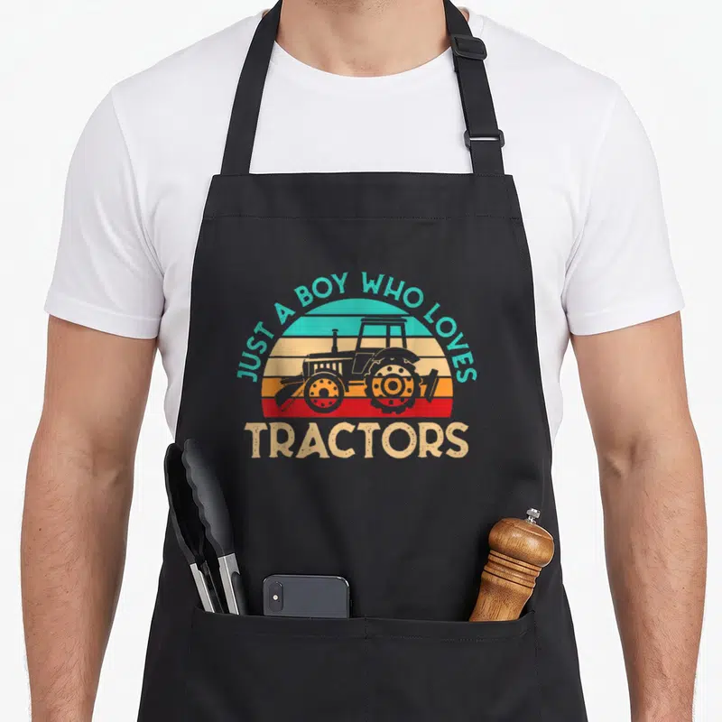 Nur tractor lover apron - Retro tractor silhouette against teal beige orange and red striped sunset with arched text — shown on a black cotton canvas apron against a white background
