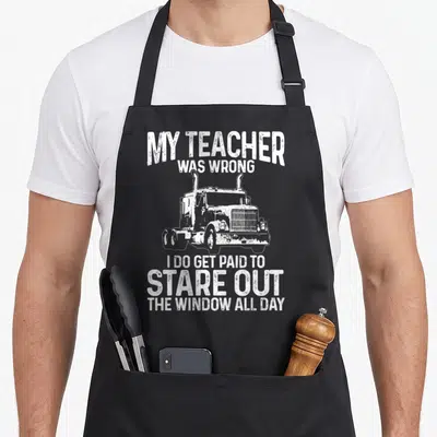 Rig truck apron - White distressed semi-truck with MY TEACHER WAS WRONG text — shown on a black cotton canvas apron against a white background