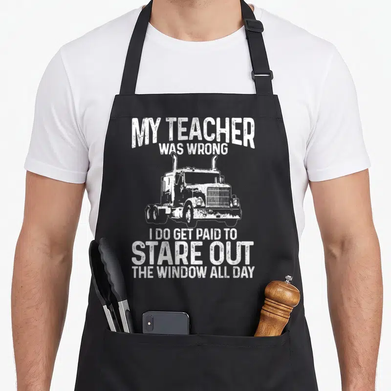 Rig truck apron - White distressed semi-truck with MY TEACHER WAS WRONG text — shown on a black cotton canvas apron against a white background