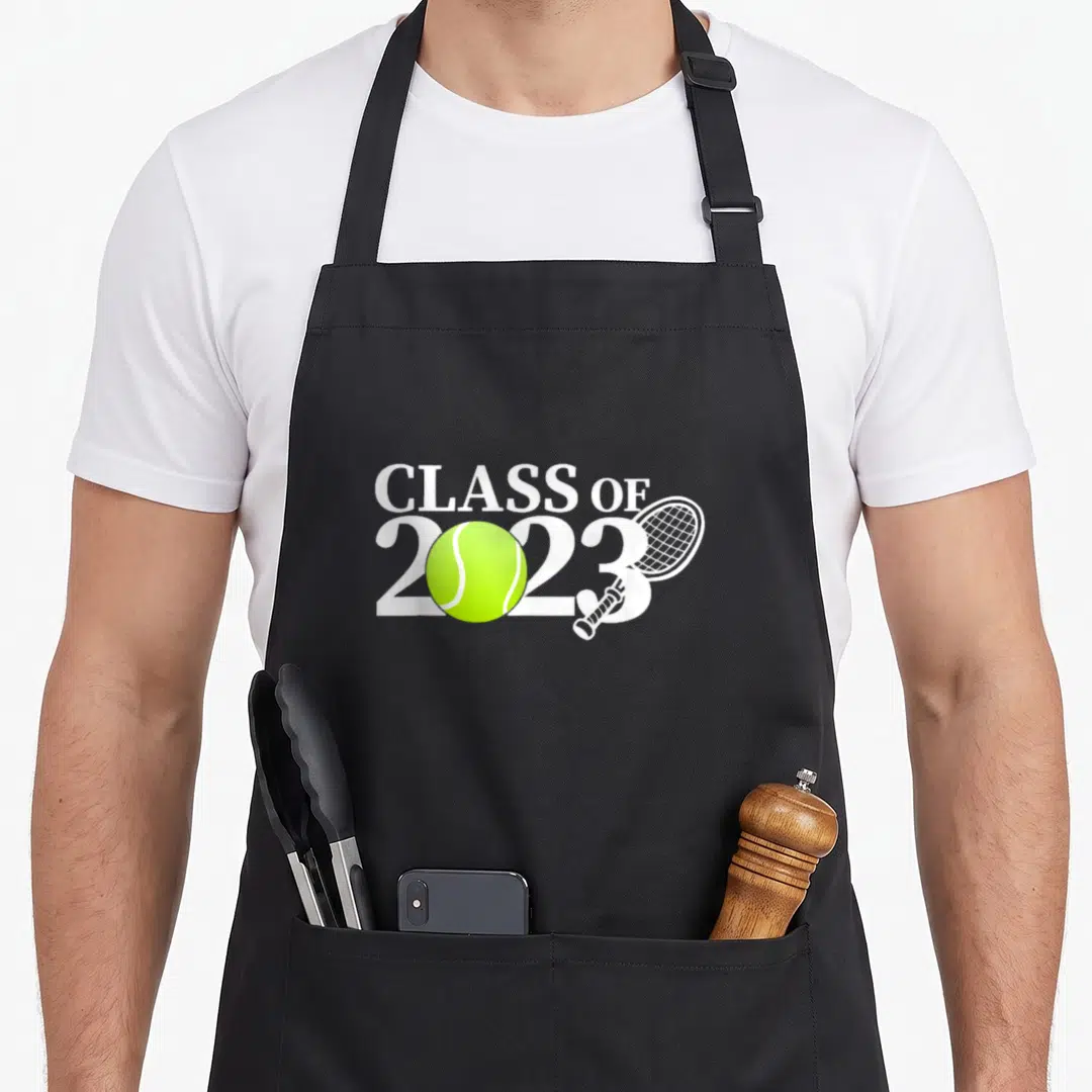 Class racquetball apron - CLASS OF 2023 text with lime green tennis ball and white racket overlapping the year digits — shown on a black cotton canvas apron against a white background