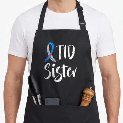 Sister diabetes awareness apron - Blue grey ribbon with red heart and white T1D Sister text — shown on a black cotton canvas apron against a white background