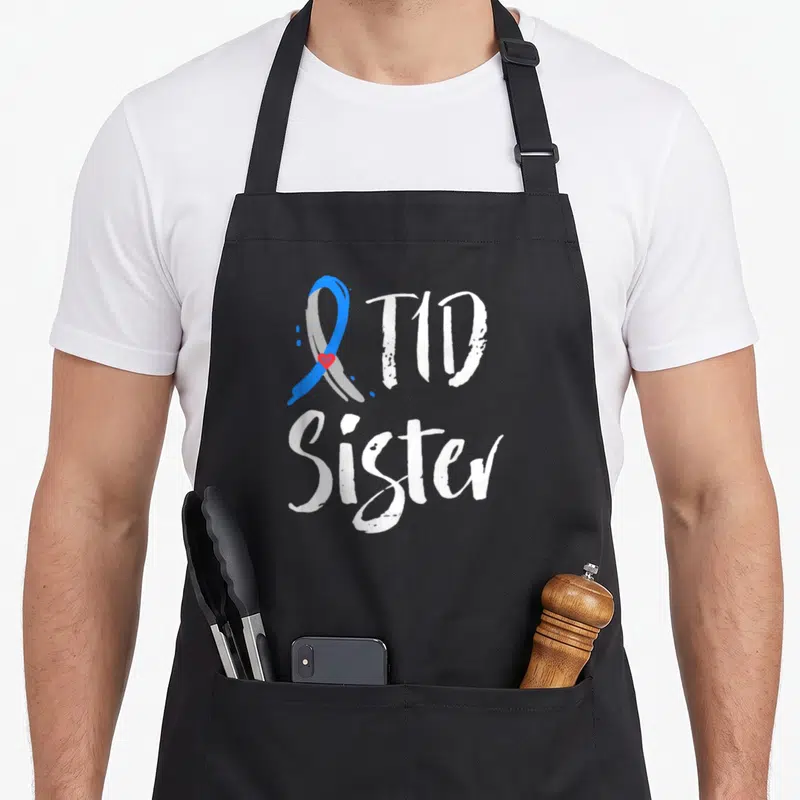Sister diabetes awareness apron - Blue grey ribbon with red heart and white T1D Sister text — shown on a black cotton canvas apron against a white background