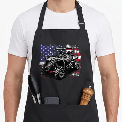 Utv 4th of july apron - Black and white UTV graphic over distressed red white and blue American flag pattern — shown on a black cotton canvas apron against a white background