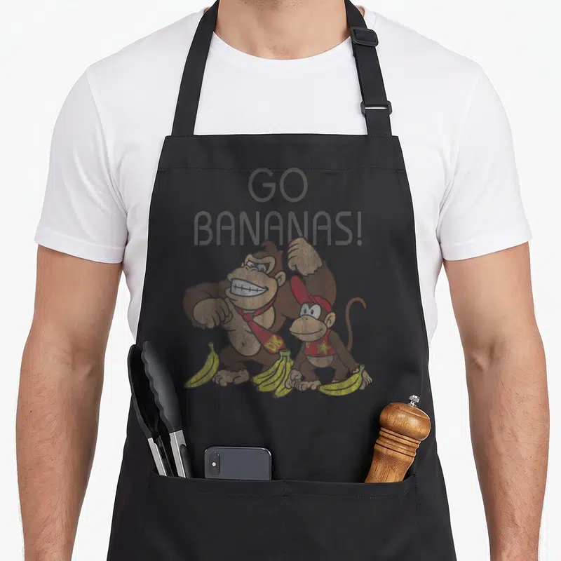 Bananas banana for men women kids apron - Donkey Kong and Diddy Kong with yellow bananas and Go Bananas text — shown on a black cotton canvas apron against a white background