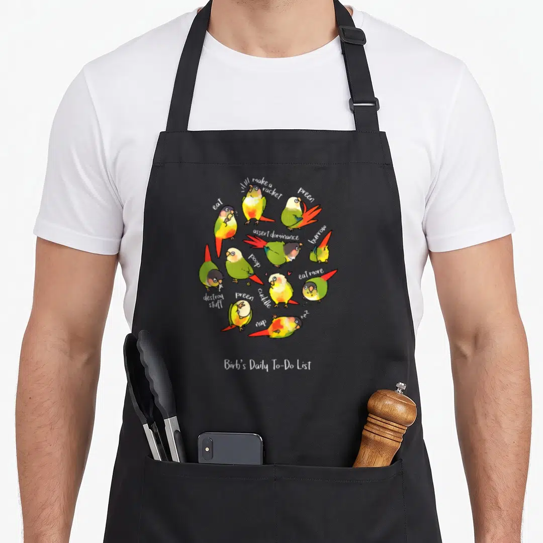 Cheek daily apron - Eleven cartoon birds in green yellow red and white arranged in a circle with action words like eat — shown on a black cotton canvas apron against a white background