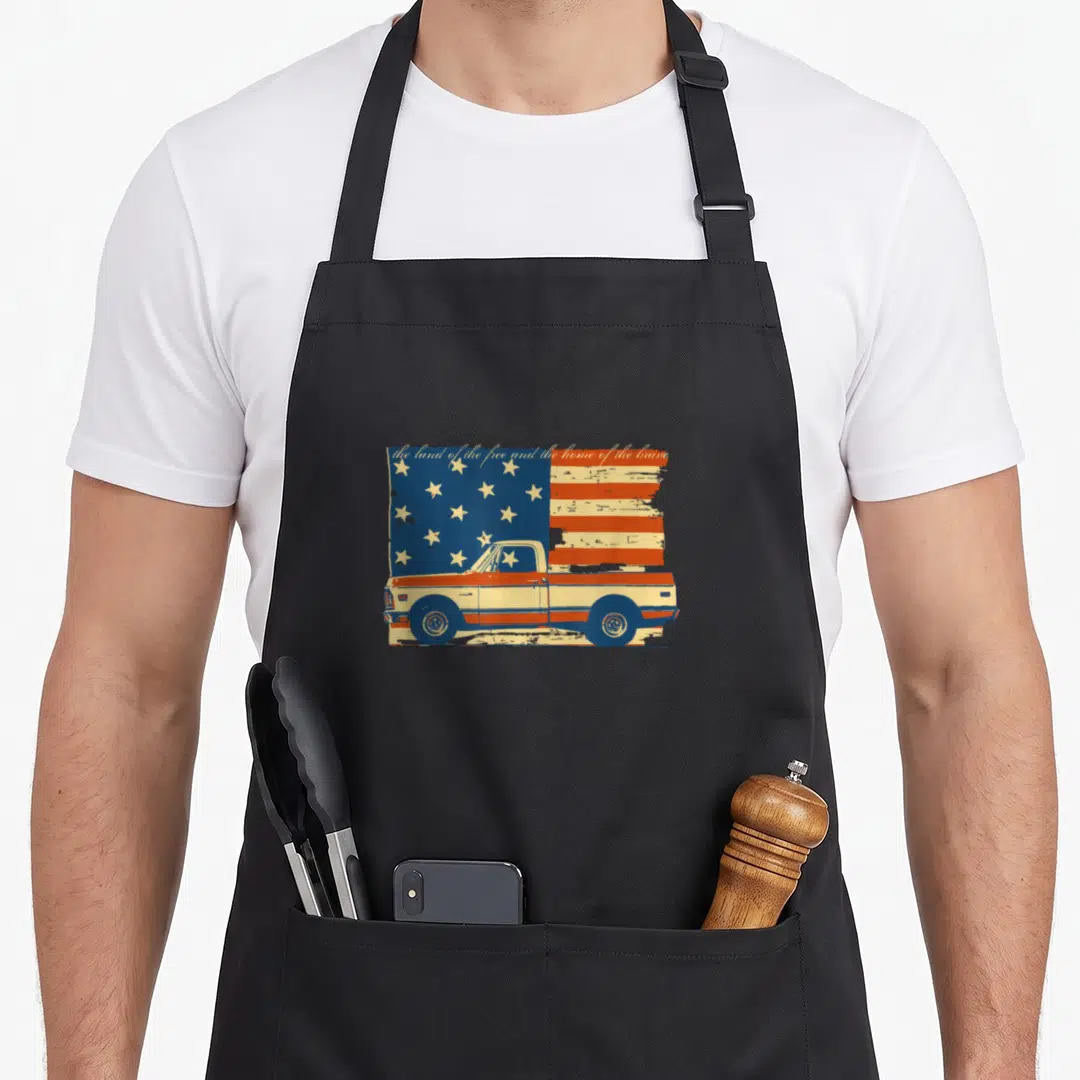 Patriotic pickup 4th of july apron - Distressed vintage pickup truck in front of USA flag with anthem lyrics in script — shown on a black cotton canvas apron against a white background