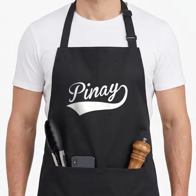 Filipina filipino apron - White Pinay text above a decorative swoosh on gray background — shown on a black cotton canvas apron against a white background