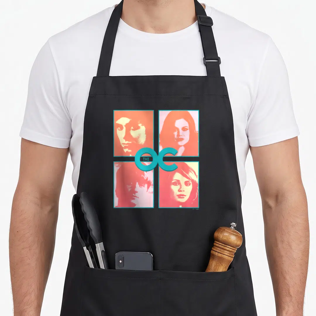 Main beach themed aprons - Four retro portraits in blue red yellow grid with THE OC text overlay — shown on a black cotton canvas apron against a white background
