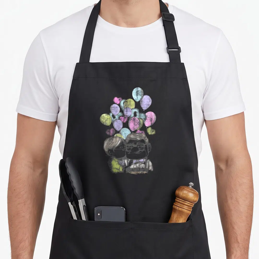 Cute carl and ellie apron - Cartoon couple kissing under cluster of pink, blue, purple, yellow, and grey heart — shown on a black cotton canvas apron against a white background