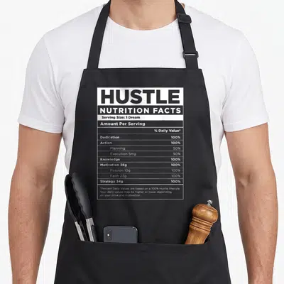 Nutrition money apron - Black and white nutrition label graphic listing Hustle ingredients like Dedication and Action — shown on a black cotton canvas apron against a white background