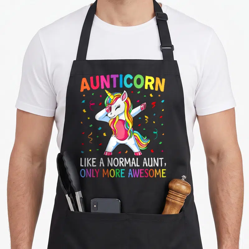 Aunticorn aunt unicorn apron - Dabbing unicorn with rainbow mane and text like a normal aunt only more awesome — shown on a black cotton canvas apron against a white background