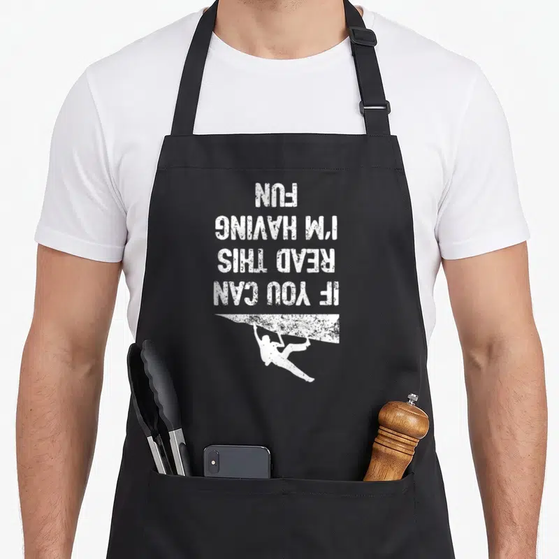 Workout bouldering apron - Upside down white text above a hanging climber silhouette in distressed style — shown on a black cotton canvas apron against a white background