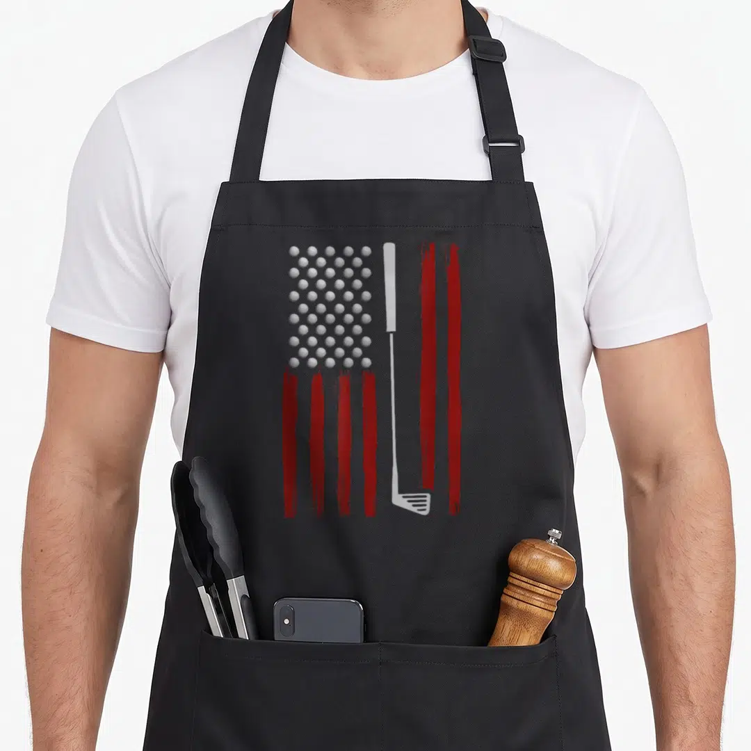 Flag golf apron - Distressed red and white flag stripes split by a white golf club with a grid of balls replacing — shown on a black cotton canvas apron against a white background