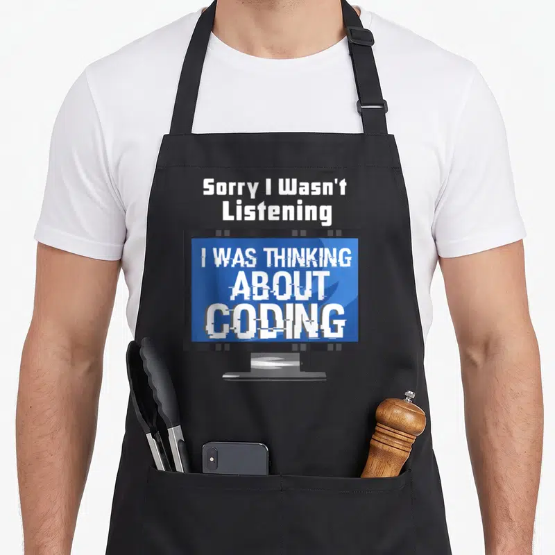 Coding programming apron - Cartoon monitor with glitch text Sorry I Wasn't Listening I Was Thinking About Coding — shown on a black cotton canvas apron against a white background